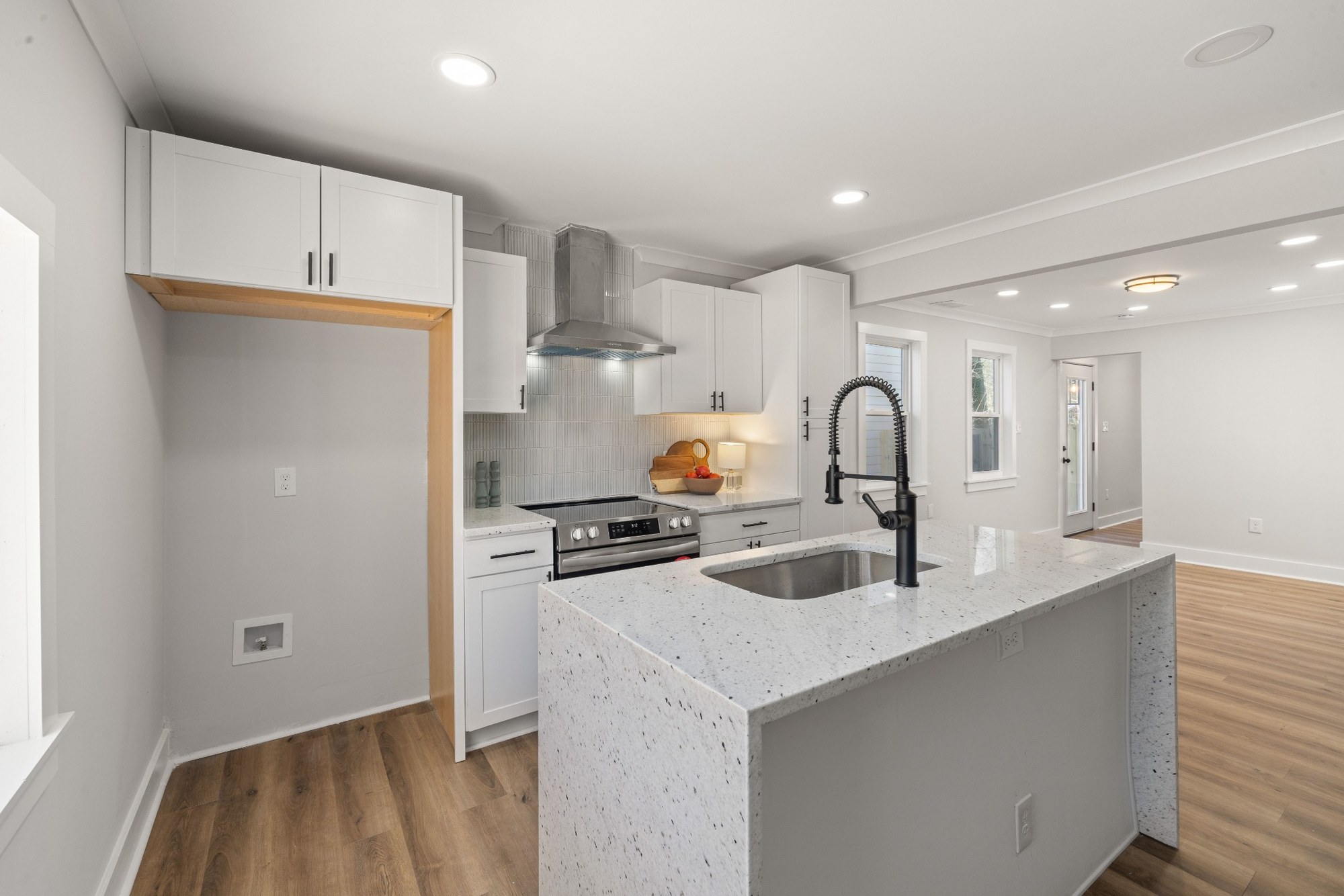 Stock image White kitchen with stone island, black faucet, and stainless appliances in Northern California - optimized