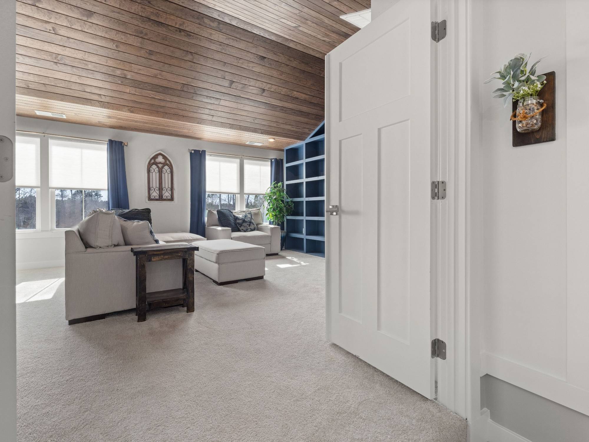 Stock image of a bonus room with wood ceiling, blue built-in shelving, large windows, and lounge seating in Northern California - optimized