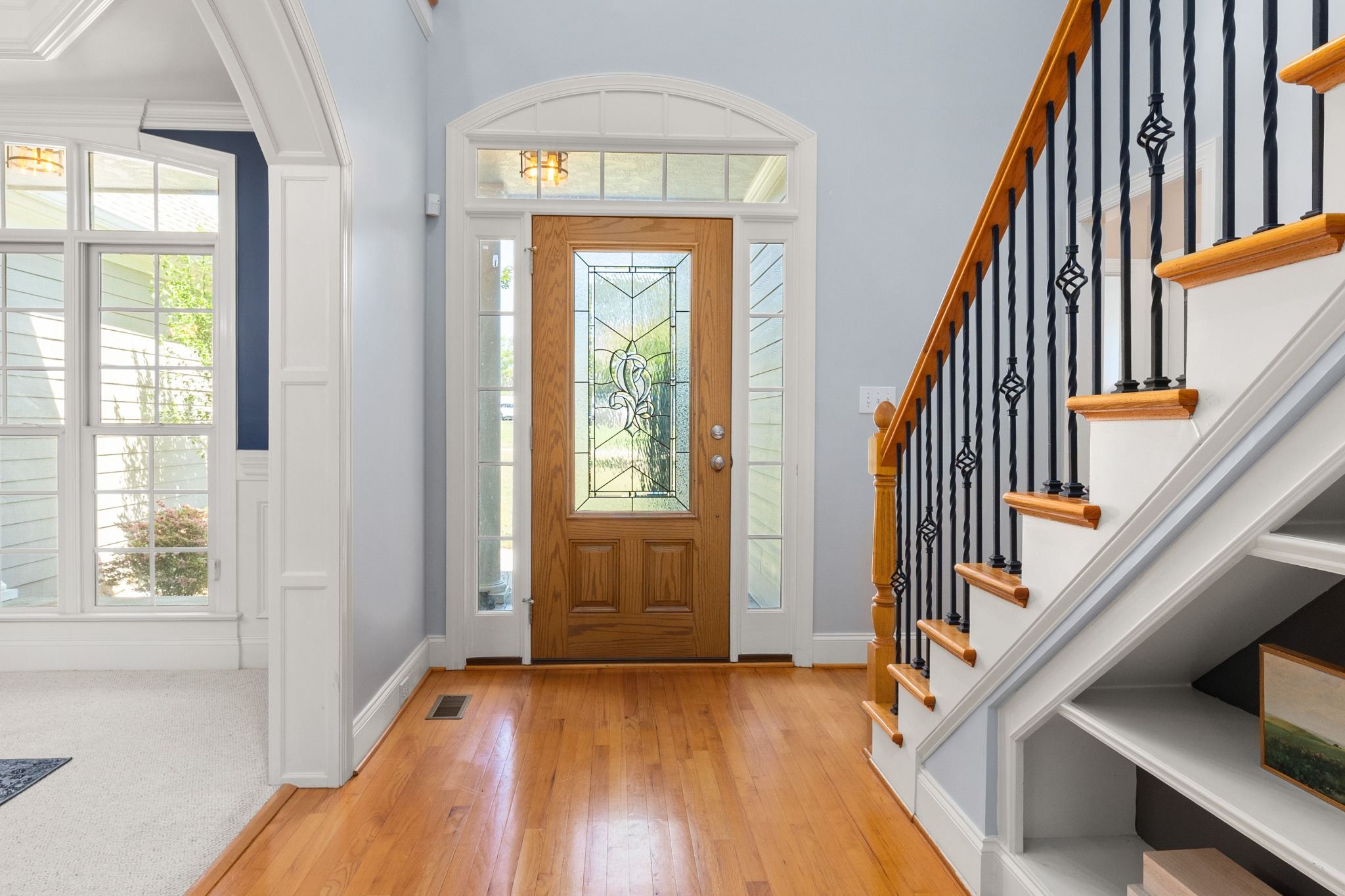 Stock image of a bright entryway with wood front door, hardwood floors, and staircase in Northern California -optimized