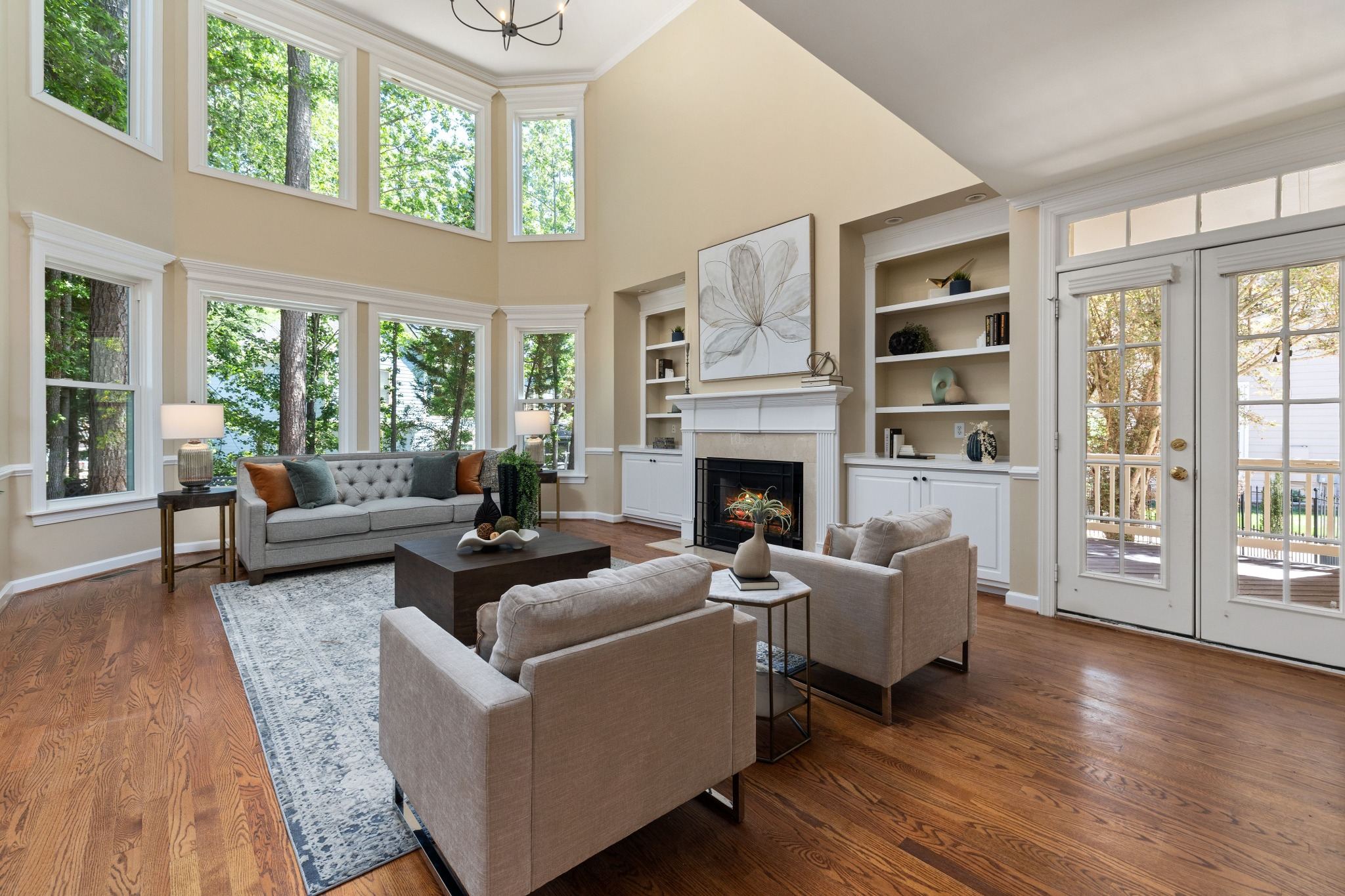 Stock image of a two-story living room with tall windows, fireplace, and French doors in Northern California -optimized